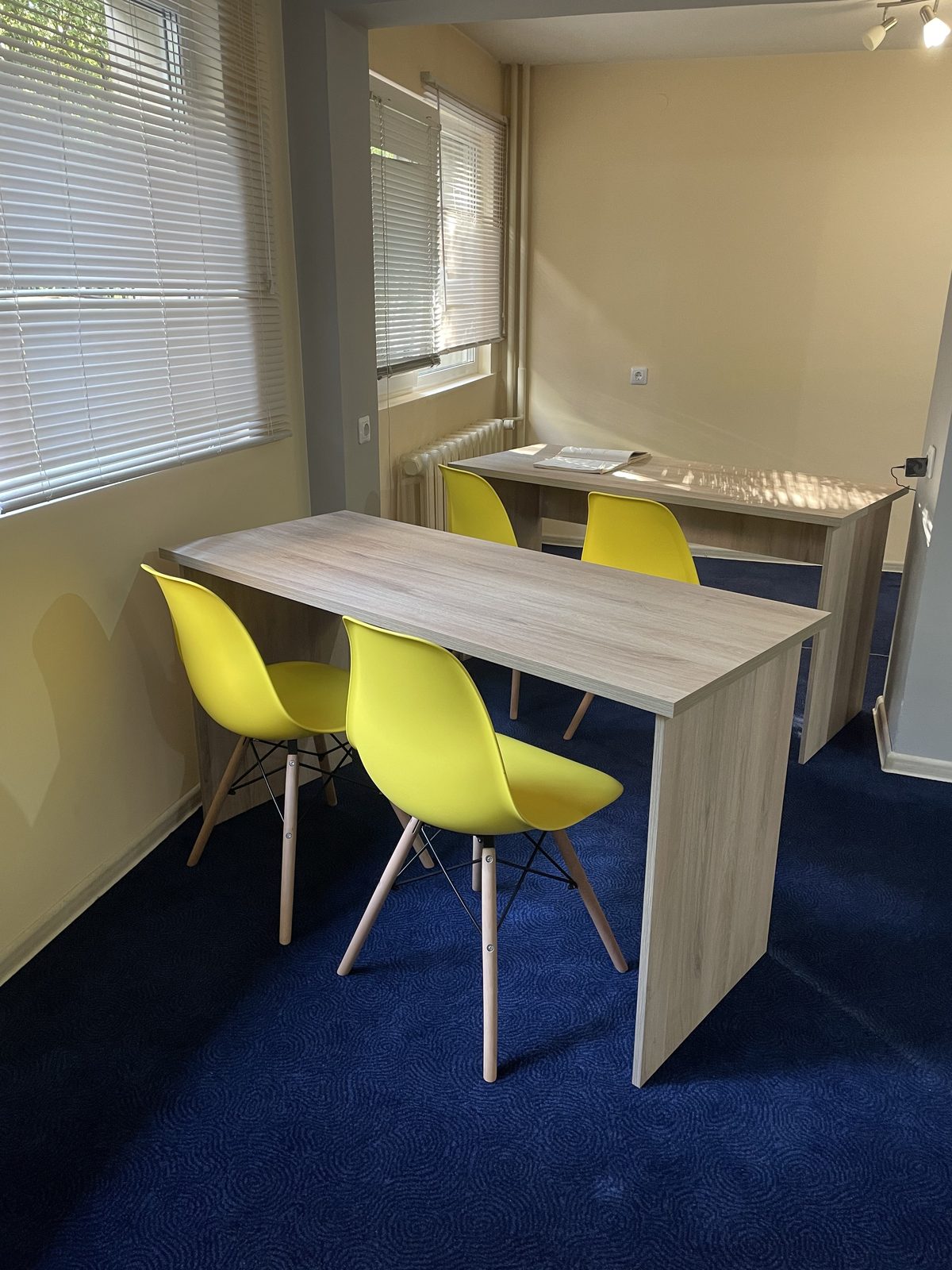 Учебната зала с масата и жълтите столчета